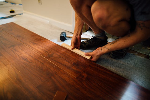 person kneeling while installing brown flooring