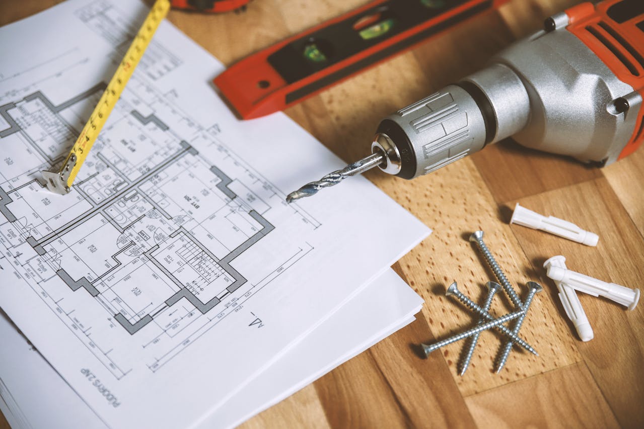 screwdriver with nails and home building plans for rental property renovations and maintenance
